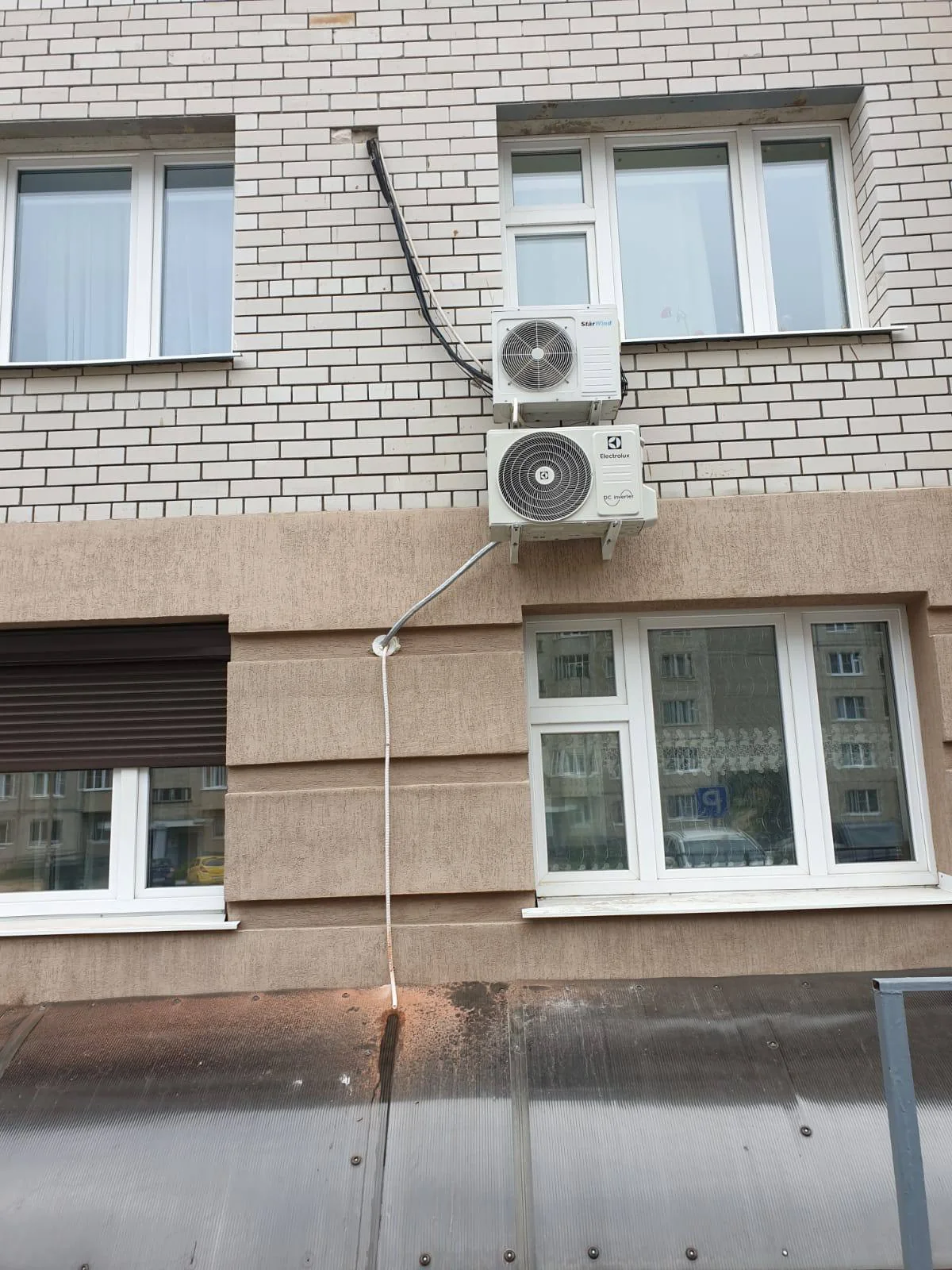 Два наружных блока расположены вертикально между окнами кирпичного фасада