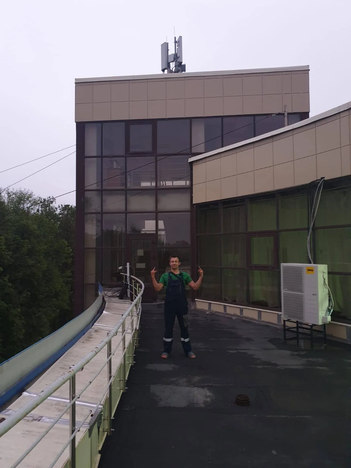 Установленный наружный блок на плоской кровле; рядом стоит монтажник
