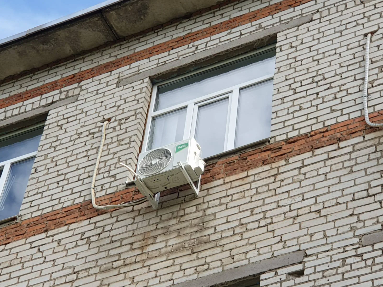 Наружный блок под окном и открыто проложенная по старой кирпичной стене трасса
