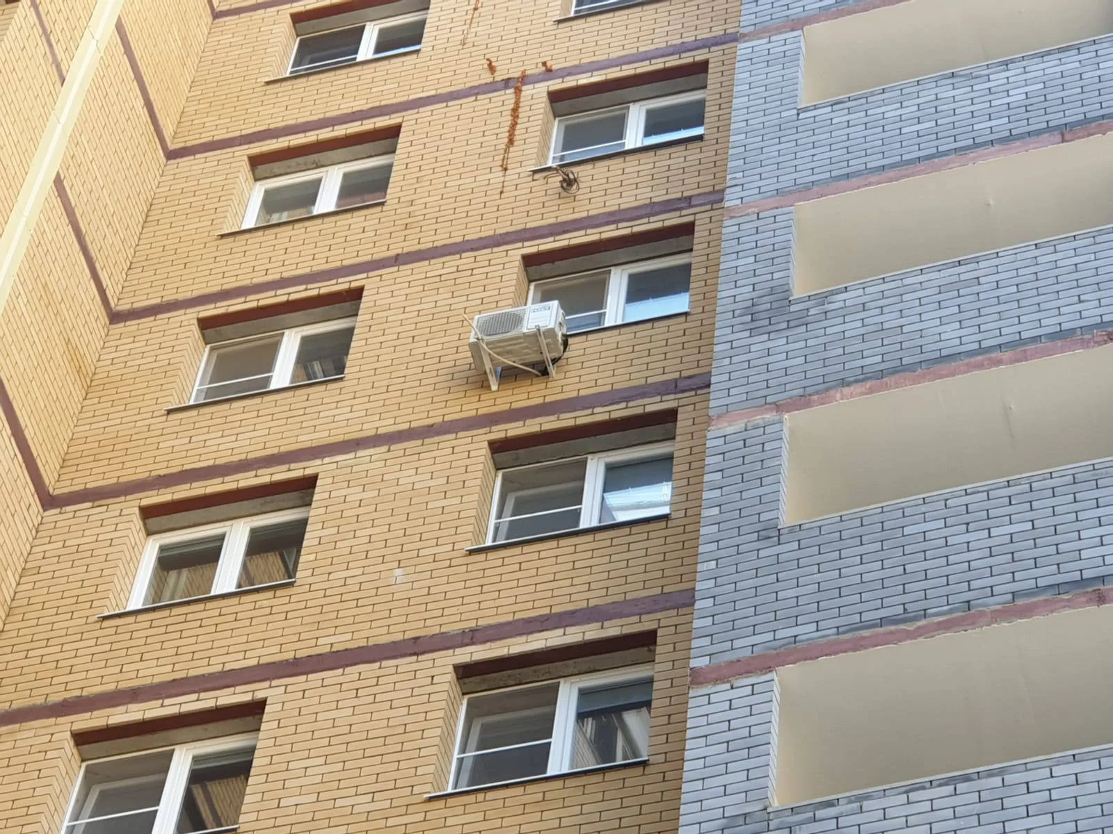 Наружный блок под окном на верхнем этаже многоэтажного кирпичного дома